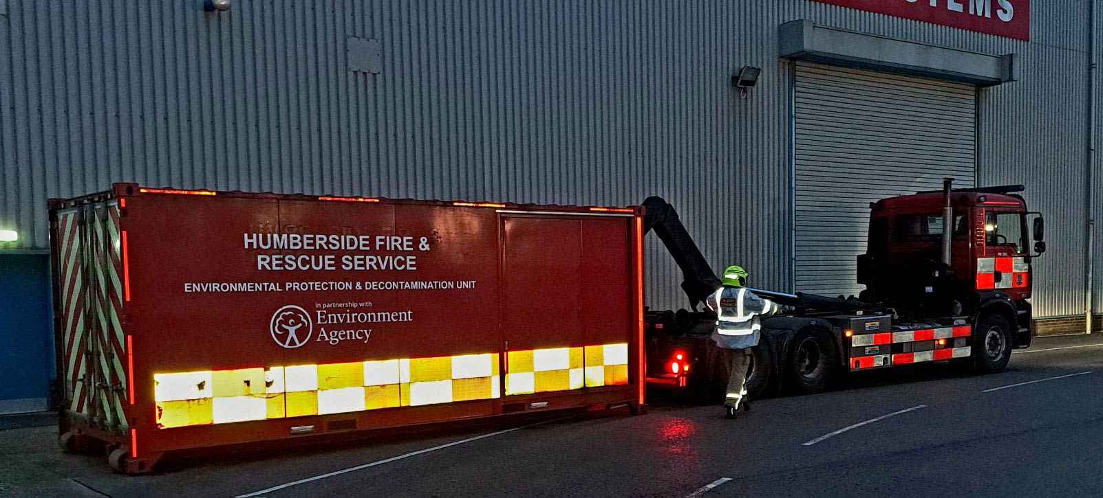Humverside Fire & Rescue Service decontamination unit being hooked up to lorry by firefighter